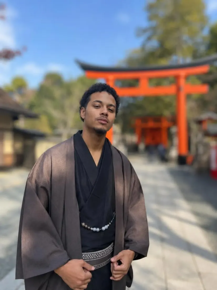 A man in a brown kimono-style robe stands before a red torii gate, before the Background Enhancer improves the backdrop.