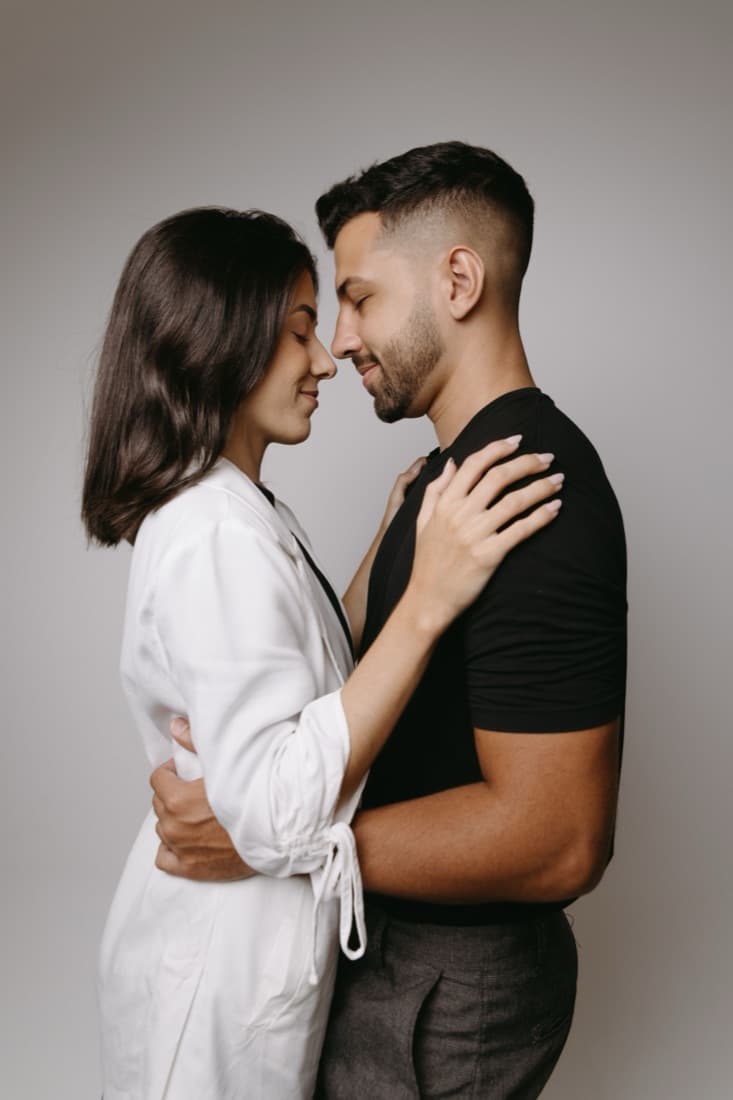 A couple embrace in a white shirt and a black t-shirt against a gray studio backdrop, before the Cultural Wedding Filter restyles them.