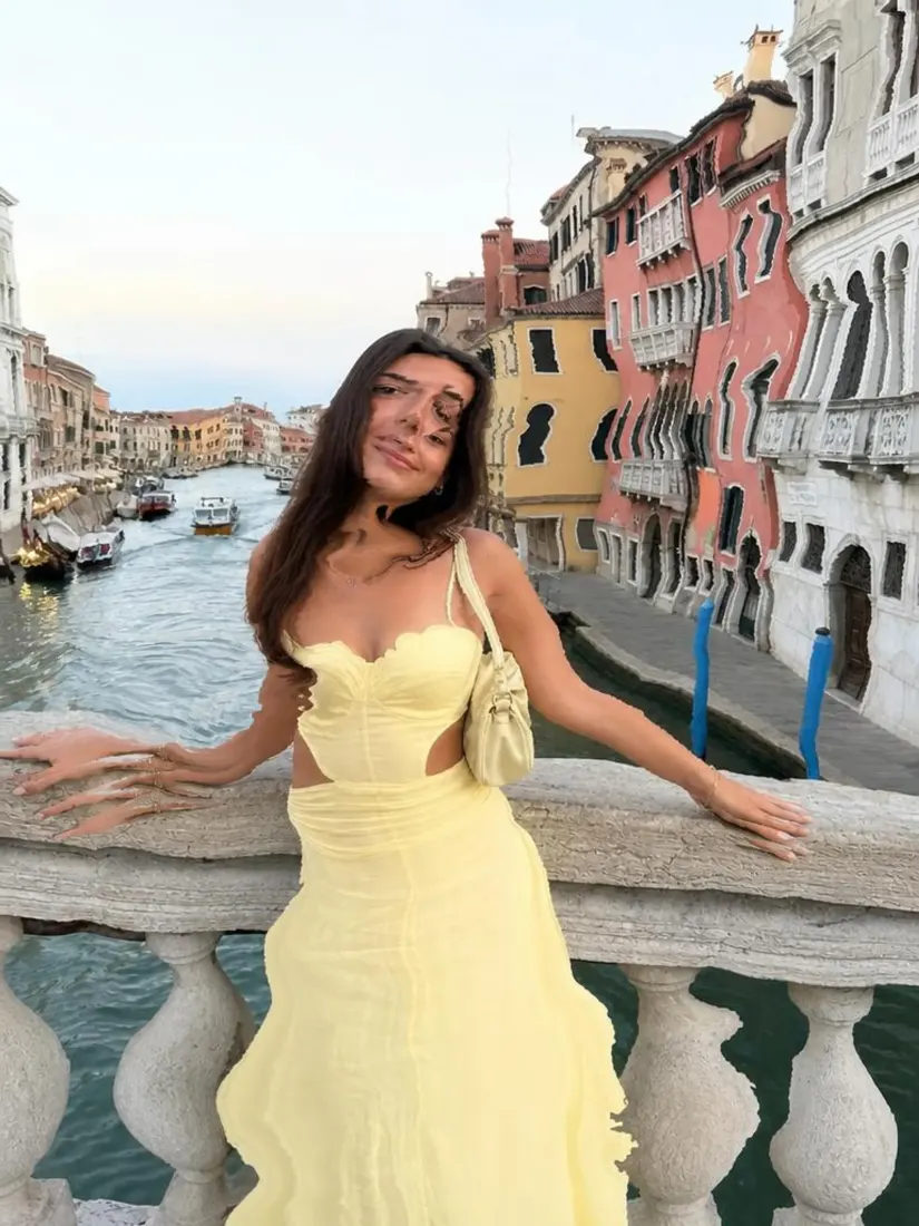 A woman in a yellow gown appears warped on a Venice balcony, before the Distortion Remover fixes the proportions.
