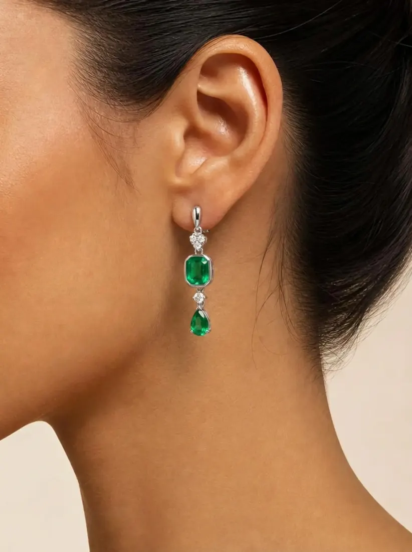 A close-up of an ear shows an emerald and diamond drop earring generated by the Earring Generator tool.