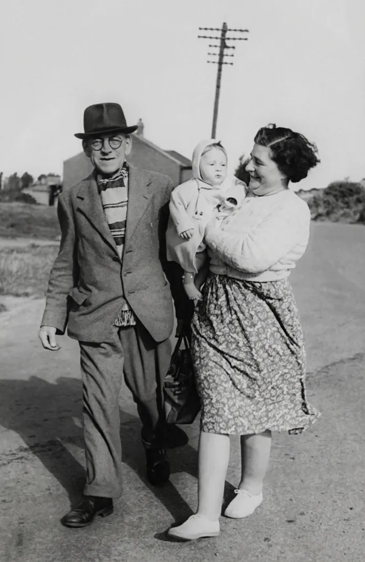 A damaged black-and-white photo shows a man walking with a woman and baby, before the Old Photo Restoration tool repairs it.