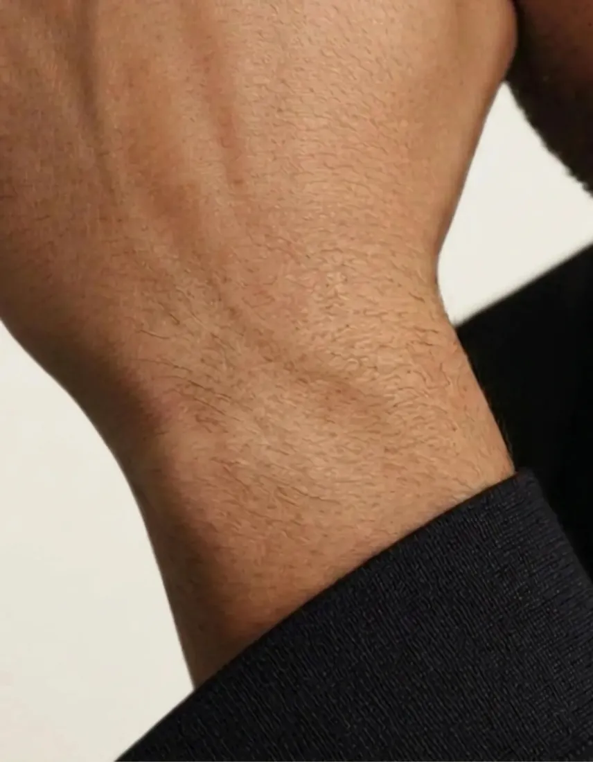 A close-up of a bare wrist in a dark sleeve, before the Watch Generator adds a watch.